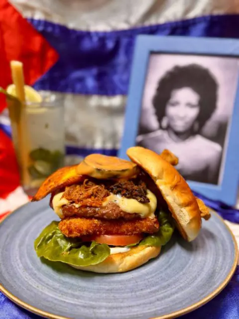 Hamburguesa El Coscorrón de Celia frente a una foto de Celia Cruz y la bandera de Cuba